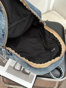 Spacious washed blue denim backpack with internal zipper pocket and fringed edge detail
