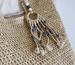 Detalle de bolso de paja trenzada con borla de ojo turco y colgante de aro de madera