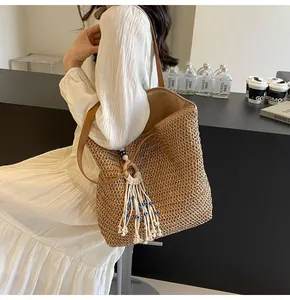 Detail of hand-woven straw tote with leather strap and blue evil eye tassel decoration