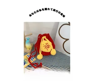 Close-up of a handmade red crochet lucky bag with yellow drawstring and Fu character