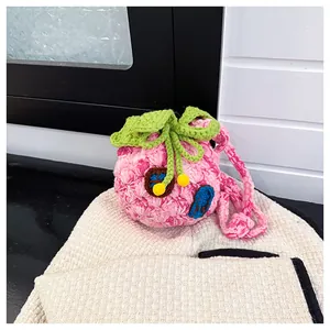 Detail of pink knitted drawstring coin purse with green leaves and creative door design