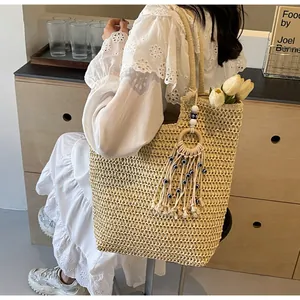 Detailed close-up of a woven straw tote bag with evil eye tassels and white tulips