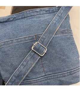 Détail de la bandoulière réglable en denim avec une boucle métallique argentée