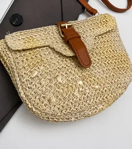 Détail du sac selle en paille avec boucle en cuir et finitions dorées chic