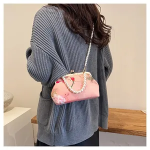 Close-up of vintage pink embroidered bag with flower bird pattern and pearl chain