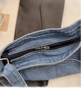 Détail de la fermeture éclair en nylon noir et tirette argentée sur sac fourre-tout en jean