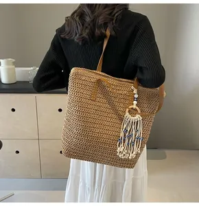 Detail of straw woven tote with leather straps and evil eye tassel charm