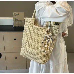Detail of handwoven straw tote with blue eye tassel charm on a white lace dress