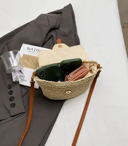 Détail de l'intérieur spacieux du sac besace en paille avec téléphone et portefeuille
