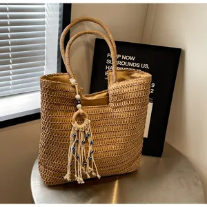 Macro detail of hand-woven straw tote bag with evil eye tassel and fabric lining