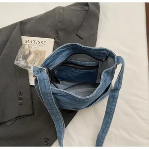 Gros plan de l'intérieur du sac en denim bleu avec fermetures éclair et poche interne