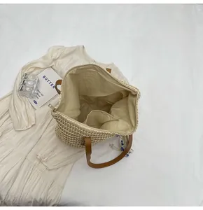 Detail of straw tote bag interior with fabric lining, inner pocket and zip closure