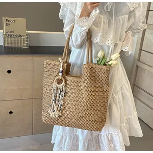Detail of hand-woven straw tote bag featuring bohemian tassel and evil eye bead charm