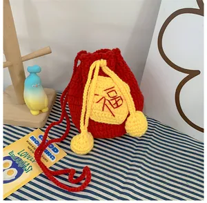 Close-up of red hand-woven crochet bag with a yellow Fu character patch and tassels