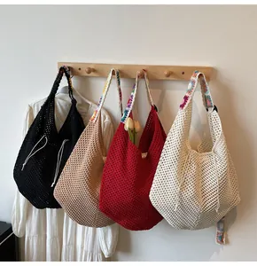 Detail der Häkelstruktur und bunte Blumenträger an großen gewebten Shopper-Taschen