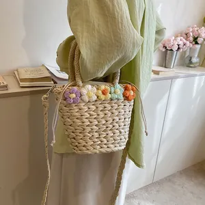 Dettaglio dei fiori all'uncinetto e della chiusura a coulisse sulla borsa di paglia