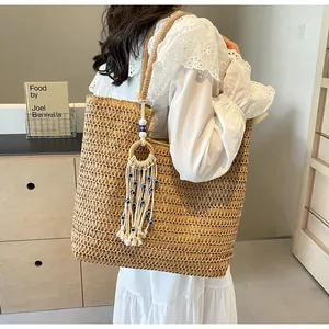 Detail of large woven straw tote bag featuring bohemian tassel and evil eye bead charm