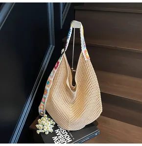 Detail of hand-woven beige hobo bag with colorful 3D crochet flowers on the shoulder strap