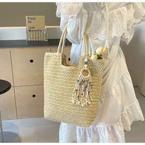 Detail of beige woven straw tote bag featuring blue beaded tassels and white tulips decoration