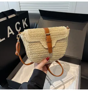 Détail de la texture en paille tressée avec bandoulière en similicuir et crochets dorés