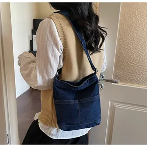 Vue détaillée du sac seau en jean bleu foncé porté en bandoulière décontractée sur un mannequin
