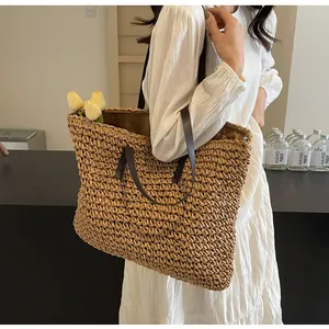Detail of a large straw tote bag with brown leather handles worn with a white summer dress