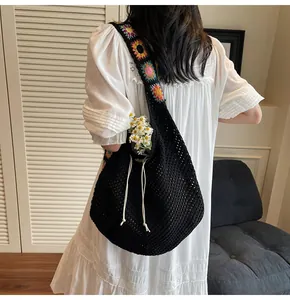 Detailed shot of crochet shoulder bag with colorful floral strap on model wearing white dress