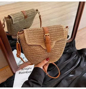 Détail du sac de selle en paille tressé avec bandoulière en cuir brun et accents dorés