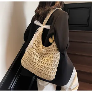 Détail du sac en paille tissé ajouré avec un délicat nœud en dentelle blanche pour l'été