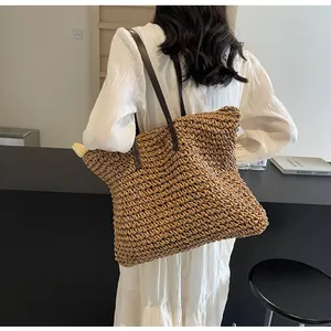Detailed view of the large straw tote bag featuring brown leather shoulder straps