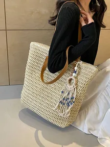 Straw tote bag with brown leather straps and evil eye charm for beach vacations