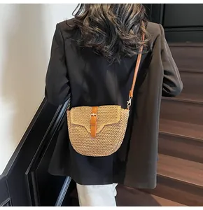 Détail du sac à bandoulière en paille tressée avec sangle en cuir brun et boucle en métal