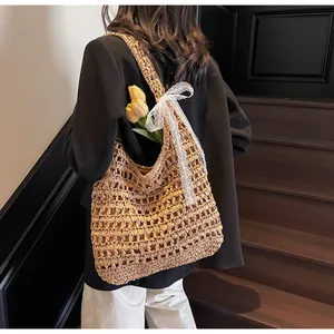 Détail du grand sac à bandoulière tissé ajouré avec un nœud en dentelle blanche