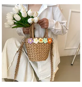 Dettaglio della borsa a secchiello in paglia con decorazioni floreali colorate all'uncinetto