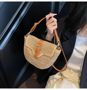 Détail du sac selle en paille avec garniture en cuir brun et boucle en métal sur la sangle