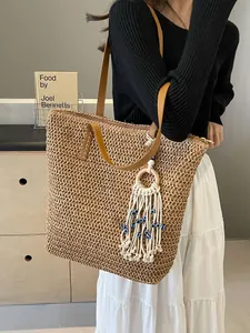 Minimalist straw tote bag with leather straps and bohemian evil eye tassel charm