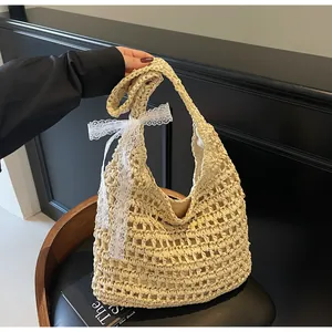 Détail d'un sac à bandoulière en paille tissé à la main avec un nœud en dentelle blanche
