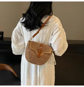 Détail du sac à main en paille tressée avec bandoulière en similicuir brun et boucle métal