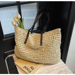 Detail of hand-woven straw tote with premium brown leather straps and floral accents