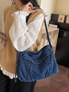 Sac cabas vintage en denim bleu avec coutures ondulées et broderie sur modèle