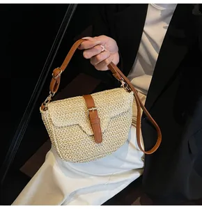 Détail du sac besace en paille tressée avec bordure en cuir marron et boucles en métal
