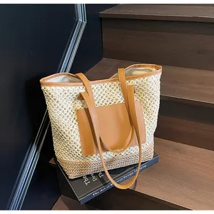 Dettaglio borsa tote in paglia intrecciata con tasca e spallacci in finta pelle marrone