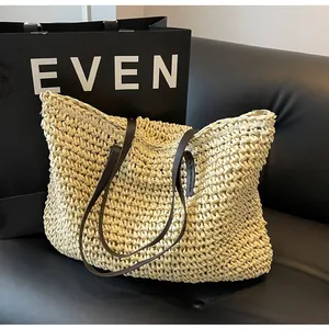 Detail of hand-woven straw texture and dark brown leather shoulder straps on a tote bag