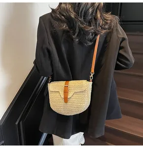 Détail du sac de selle en paille tressée beige avec bandoulière en similicuir marron