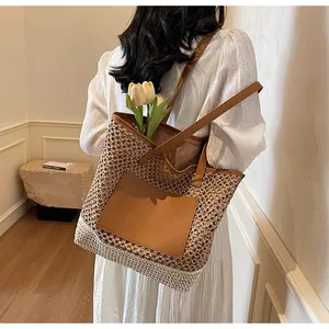 Dettaglio della borsa tote in paglia intrecciata con tasca in pelle marrone in casa