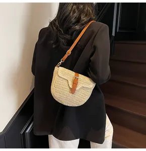Détail du sac selle en paille avec bandoulière en cuir réglable et texture tissée