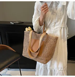 Detail der hohl gewebten Strandtasche mit Lederpatch und Doppelgriffen zum weißen Kleid