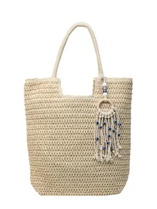 Chic woven beach tote bag in beige featuring evil eye tassel charm and shoulder straps