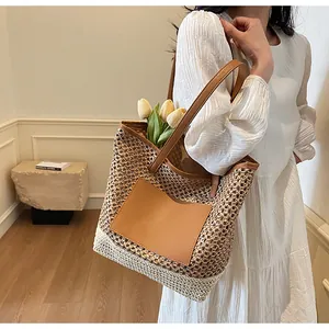 Dettaglio borsa tote in paglia intrecciata con inserto in pelle marrone e tracolla