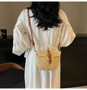 Détail du sac selle en paille avec bandoulière en cuir marron porté par un mannequin